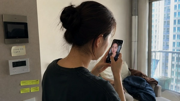 Person checking how fashion contact lenses appear indoors compared to natural daylight near a window.